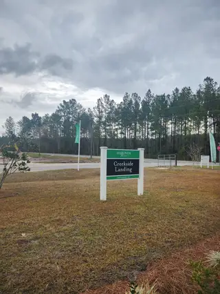 Scenic entrance to Creekside Landing by Maronda Homes, surrounded by lush greenery in Callahan, FL.