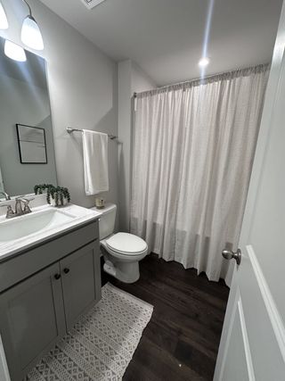 A cozy bathroom featuring a gray vanity, elegant lighting, and a soft white shower curtain.