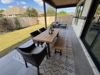 A lovely patio with a wooden table, wicker chairs, and a cozy seating area on a patterned rug, perfect for outdoor gatherings.