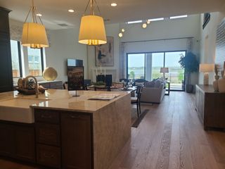 A luxurious open-concept living area with elegant lighting, a large island, and a stunning view through floor-to-ceiling windows.