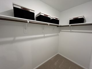 A spacious walk-in closet with built-in shelving and storage bins for organized living.