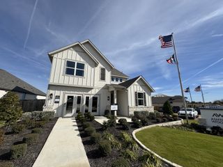Street view A charming white home with manicured landscaping in Patterson Ranch by Ashton Woods (Georgetown, TX).