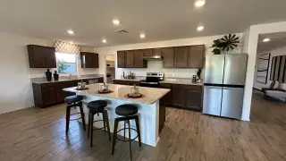A modern kitchen with granite countertops, dark wood cabinets, and stainless steel appliances, complete with a central island.