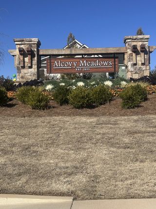Street view Stone entrance sign for Alcovy Meadows by Resibuilt in Dacula, GA, surrounded by manicured landscaping.