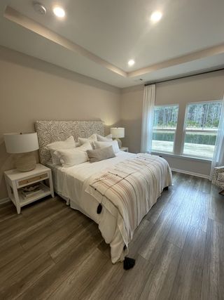 A cozy bedroom with a patterned headboard, soft lighting, and large windows showcasing a serene view outside.