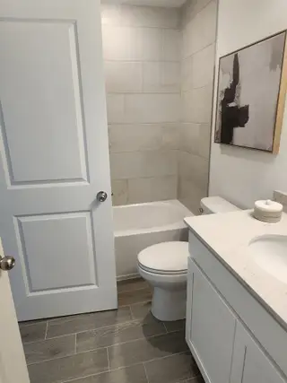 A bright and elegant bathroom with a quartz vanity, modern fixtures, and a tiled bathtub for a spa-like feel.