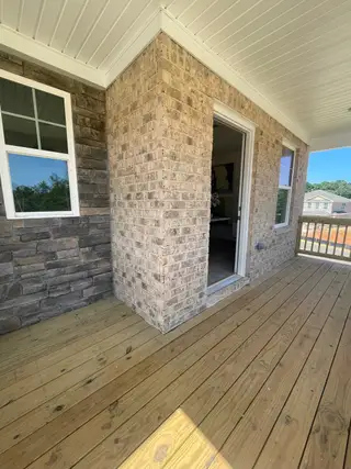 A cozy porch with brick and stone accents, featuring wooden flooring and white trim, ideal for relaxation.