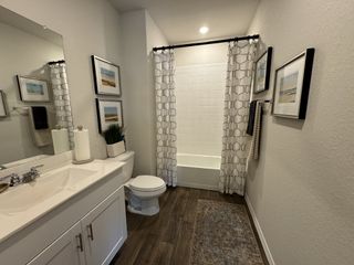 A contemporary bathroom with a tiled bathtub, white vanity, and built-in shelving for a clean and functional design.