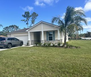 A charming single-story home with stone accents and manicured lawn in Palm Coast by Brightland Homes (Palm Coast, FL).