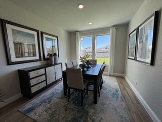 A bright dining room featuring a sleek dark table, elegant artwork, and large windows overlooking a lush backyard.