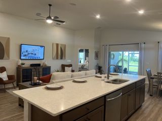 Model Home Spacious open-concept living area with sleek island kitchen, cozy seating, and abundant natural light from large sliding doors.