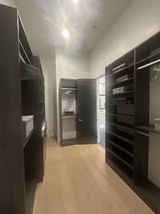 A custom walk-in closet with dark wood shelving, ample hanging space, and soft recessed lighting for a boutique-style feel.