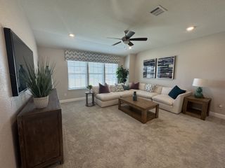 A cozy living room with plush carpeting, a large sectional sofa, an table, and a decorative TV console, creating a comfortable gathering space.