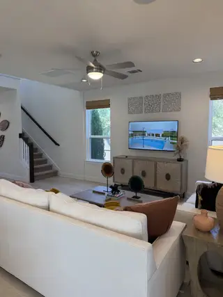 A cozy living room with a sleek ceiling fan, modern decor, and a large TV above a stylish console.