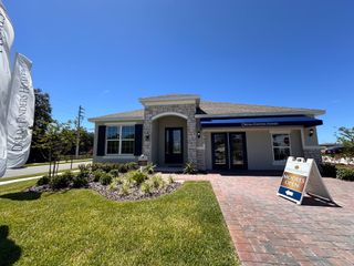 A charming model home with a stone facade and lush landscaping in Prairie Oaks by Dream Finders Homes (St. Cloud, FL).