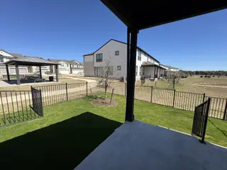 Model Home A scenic backyard view with a fenced lawn, covered patio, and a walking path leading to a community gazebo.