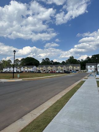 Street view A scenic street with new build homes in Avery Landing by DRB Homes, Mcdonough, GA, under a beautiful blue sky.