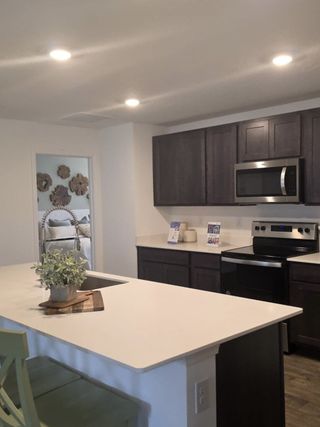 Model Home A modern kitchen with dark cabinets, stainless steel appliances, and a sleek white island.