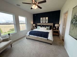 Model Home A cozy bedroom with a tufted bed, elegant blue accent wall, and natural light from large windows.
