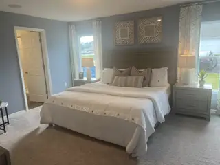 A cozy bedroom with serene gray walls, plush carpeting, and soft lighting, featuring a wooden bed and elegant decor.