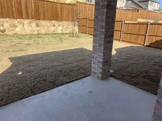 A covered patio with a brick column, overlooking a private fenced backyard in Woodmere by M/I Homes (Denton, TX).