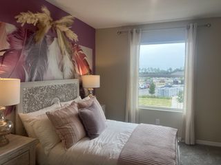 A cozy bedroom featuring a decorative headboard, elegant lamps, and soft textiles, highlighted by a vibrant feather mural.