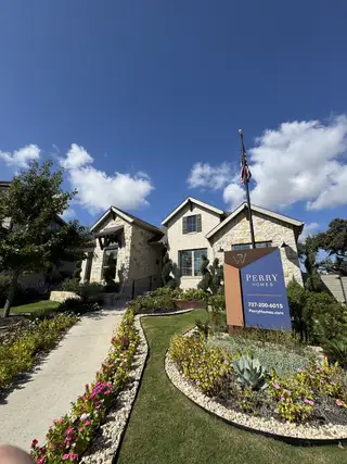 Street view A charming stone facade home with vibrant landscaping in Wolf Ranch 56' by Perry Homes (Georgetown, TX).