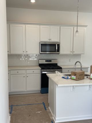 A modern kitchen with white cabinets, stainless steel appliances, and a sleek subway tile backsplash.