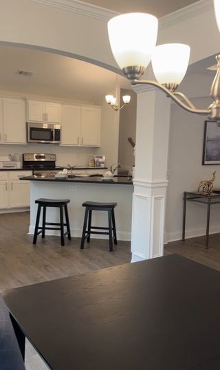 An elegant kitchen with white cabinetry, black countertops, and bar seating in Covington by Castle Homes (Savoy Park, GA).
