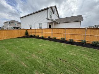 A charming white home with a fenced yard and manicured lawn in Cool Water by M/I Homes (Jarrell, TX).