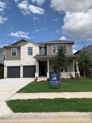Street view A modern two-story home with stone and siding facade in Saddleback at Santa Rita Ranch by Pulte Homes (Liberty Hill, TX).