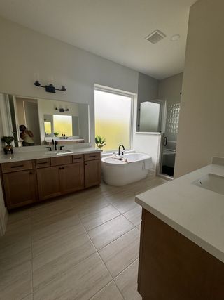 A spacious bathroom featuring a freestanding tub, dual sinks with wooden cabinetry, and a large mirror.