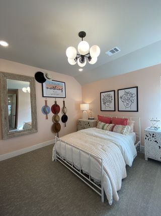 A cozy bedroom with pastel walls, chic decor, and an elegant chandelier. Features a vintage-style bed and decorative wall art.