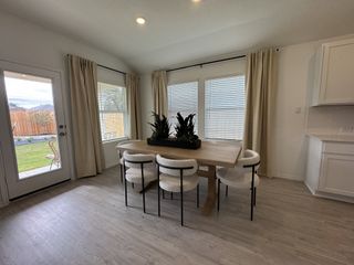 A chic dining area with a wooden table, modern chairs, and large windows overlooking a lush backyard.