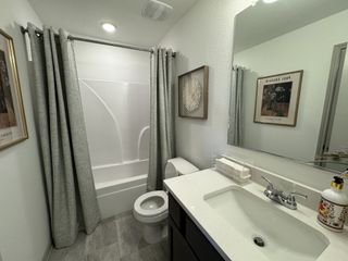 A stylish bathroom features a modern vanity, framed artwork, and a shower with a gray curtain, offering a blend of comfort and contemporary design.