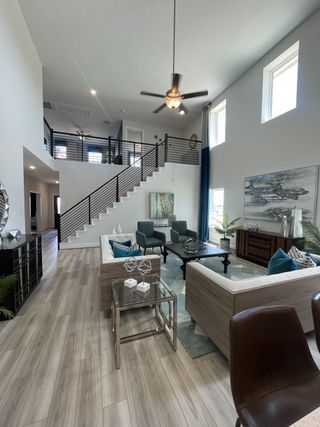 A spacious living room with high ceilings, modern decor, natural light, and stylish furniture.