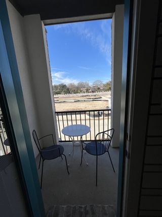 A cozy balcony featuring sleek metal chairs and a round table, perfect for enjoying outdoor views and relaxation.