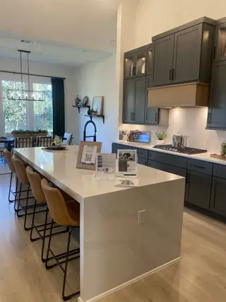 Modern kitchen with sleek dark cabinets, a spacious island with seating, and natural light from large windows.