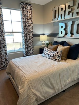 A cozy bedroom featuring bold "Dream Big" decor, patterned curtains, and plush bedding for a relaxing atmosphere.