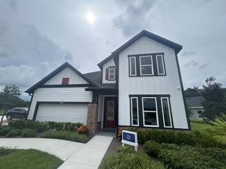 A modern white home with bold trim and a lush garden in Oakfield at Mount Dora Cottage Series by David Weekley Homes (Mount Dora, FL).