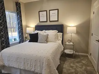 A cozy bedroom with a plush bed, elegant side tables, soft lighting, and decorative curtains. Perfect for relaxation.