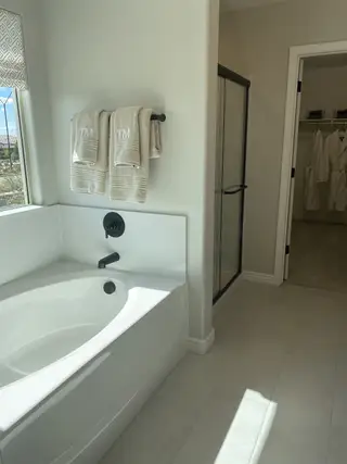 A bathroom with a soaking tub, glass-enclosed shower, and dual monogrammed towels offers a spa-like feel with clean lines and modern fixtures.