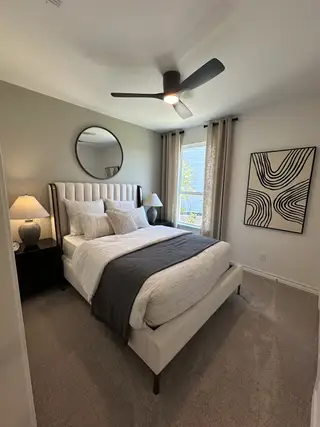 A cozy bedroom featuring a plush bed, modern ceiling fan, and stylish decor with neutral tones.