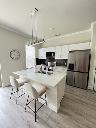 Model Home A modern kitchen with a sleek island, stainless appliances, and stylish pendant lighting offers a chic cooking space.