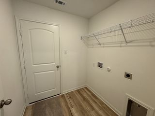 A utility room with a white door, wire shelf, and wood-look flooring.