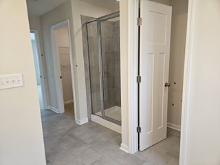 Model Home Modern bathroom with a glass shower, tiled flooring, and white doors leading to adjacent spaces.