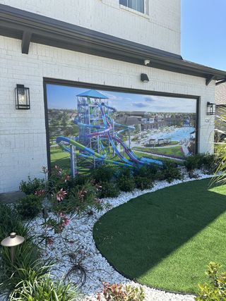 Street view A modern white brick home with lush landscaping in Saint Tropez by Megatel Homes (Huffman, TX).