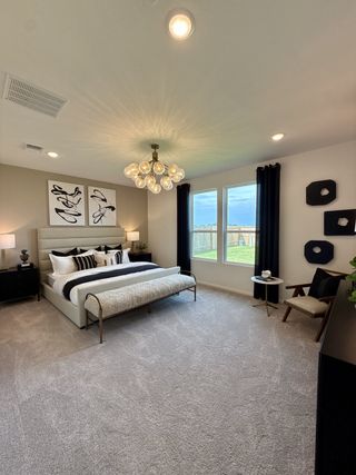 Model Home A modern bedroom with elegant pendant lighting, plush carpeting, and large windows showcasing natural light.