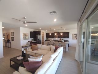 Model Home A modern open-concept living room with a cozy sectional, stylish kitchen island, and elegant pendant lighting.