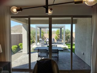 Model Home A modern patio view with sliding glass doors, elegant seating, and pergola, set against a scenic mountain backdrop.